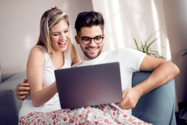 Foto pareja joven, con, computador portatil, en, el, sala