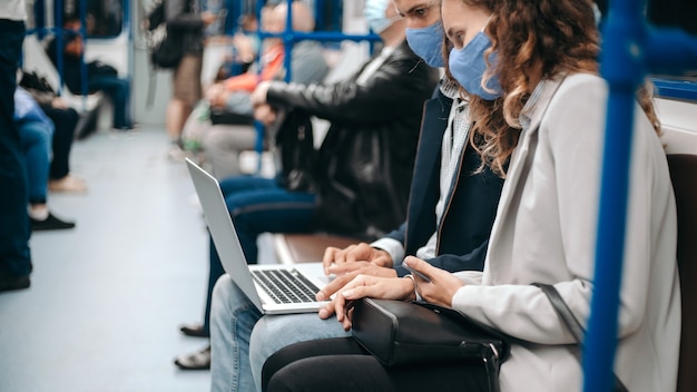 pareja joven, con, un, computador portatil, sentado, en, un, vagón de metro