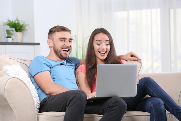 pareja joven, con, computador portatil, en, sofá, en casa