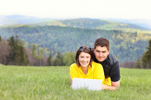 pareja joven, y, computadora portátil, en el pasto en las montañas