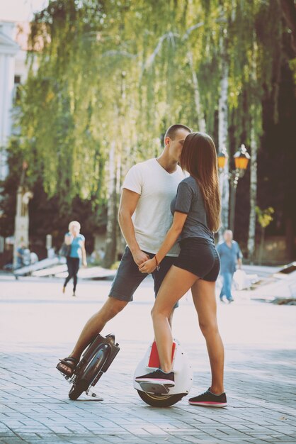 Pareja joven conduciendo en monowheel en el parque