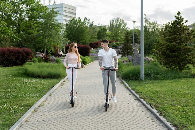 Pareja joven conduciendo un scooter eléctrico en el parque