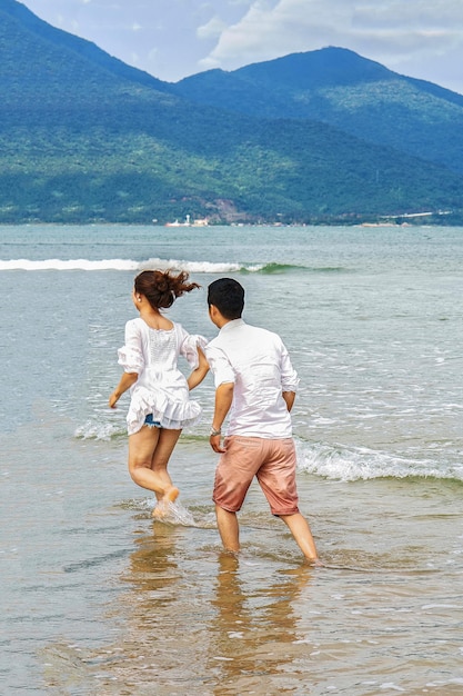 Pareja joven corriendo por el agua en la playa de China en Danang, en Vietnam