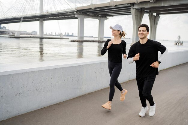 Pareja joven corriendo en el parque Entrenamiento físico en ropa deportiva y zapatillas