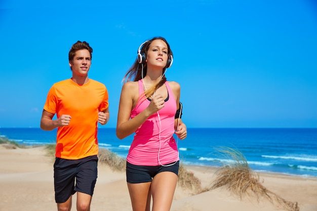 Pareja joven corriendo en la playa en verano