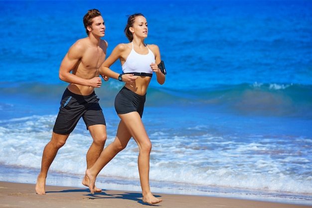 Pareja joven corriendo en la playa en verano