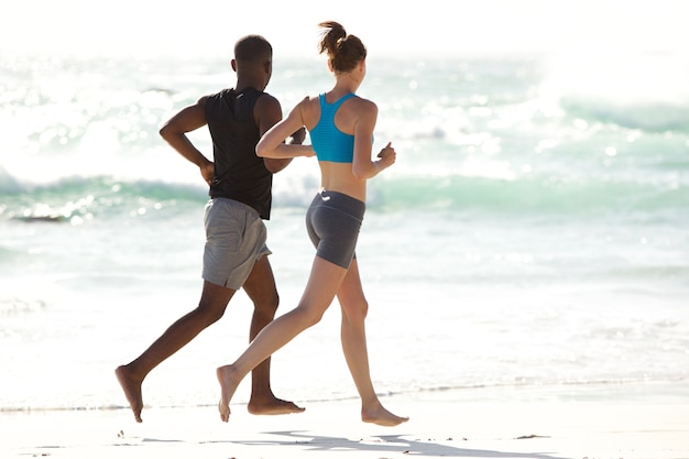 Pareja joven corriendo por la playa