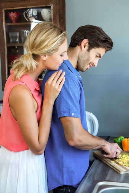 Pareja joven cortando verduras en la cocina