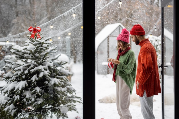 Pareja joven decora el árbol de navidad en el patio trasero