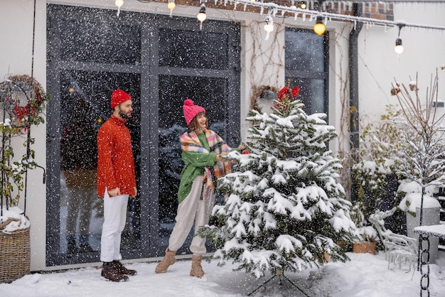 Pareja joven decora el árbol de navidad en el patio trasero