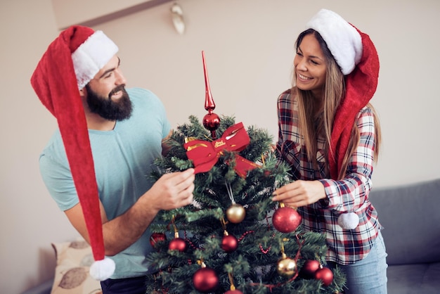 Pareja joven decorando un árbol de Navidad