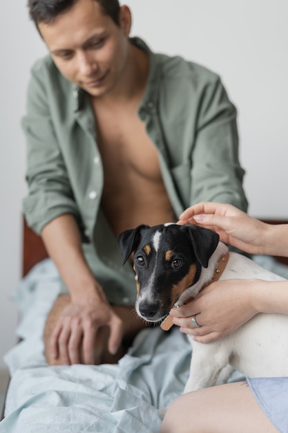 Pareja joven descansando en la cama y jugando con un perro