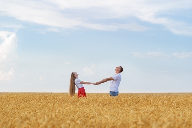 Pareja joven descansando en el campo de trigo de verano. Fin de semana romántico en campo