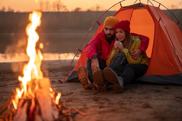 Pareja joven, descansar, en, carpa, cerca, fogata