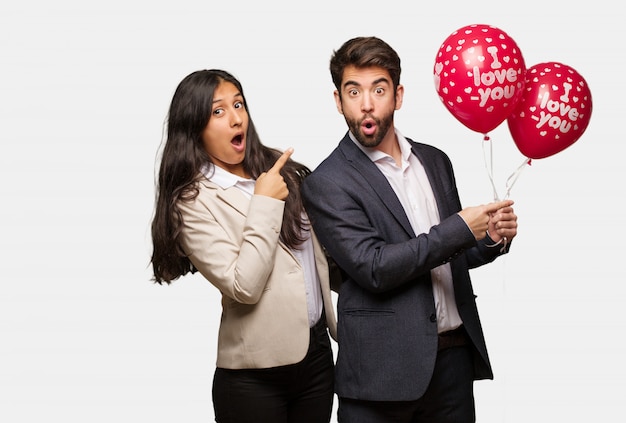 Pareja joven en el día de San Valentín apuntando hacia el lado