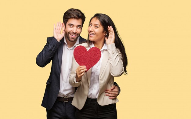 Pareja joven en el día de San Valentín intenta escuchar un chisme