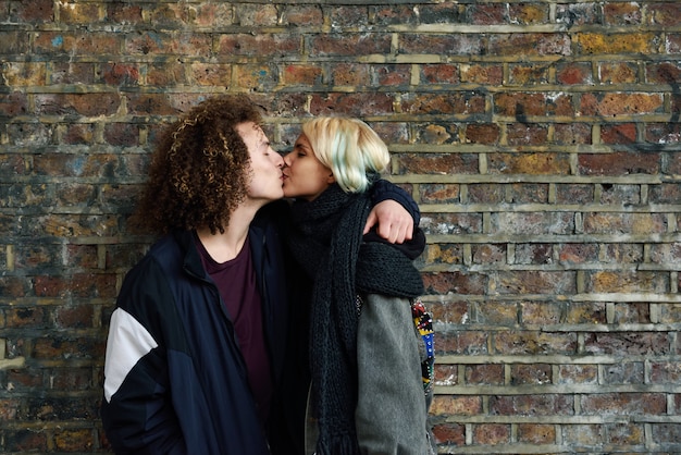 Pareja joven disfrutando de la ciudad de Camden frente a una pared de ladrillos típica de Londres