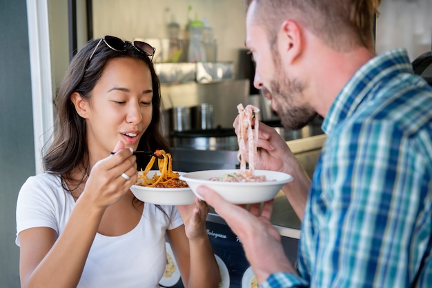 Pareja joven disfrutando comiendo pasta de comida camión