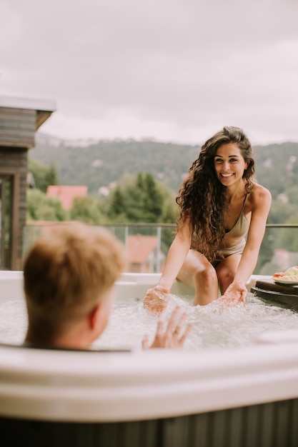 Pareja joven disfrutando en el jacuzzi al aire libre de vacaciones