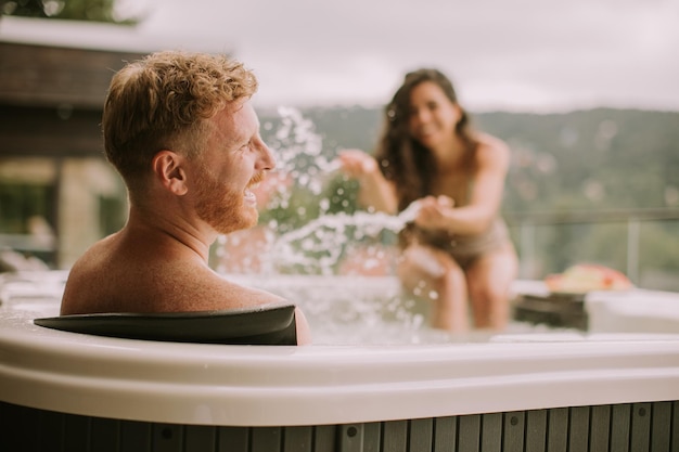 Pareja joven disfrutando en el jacuzzi al aire libre de vacaciones