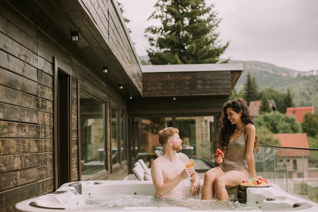 Pareja joven disfrutando en el jacuzzi al aire libre de vacaciones