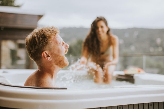 Pareja joven disfrutando en el jacuzzi al aire libre de vacaciones