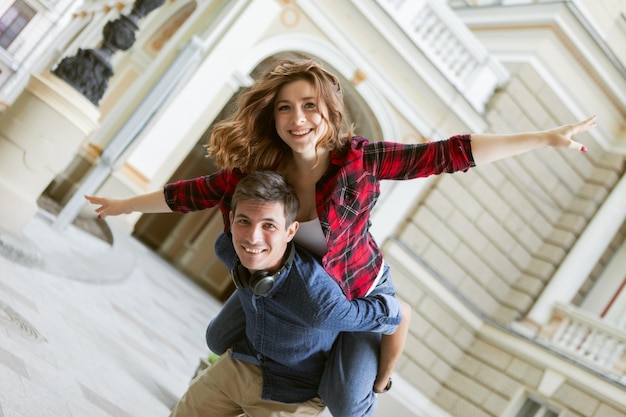 Pareja joven divirtiéndose al aire libre. Un hombre guapo dando a su novia un paseo a cuestas. Disfrutando cada momento juntos.