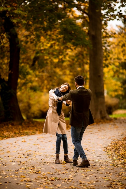 Pareja joven divirtiéndose en el parque de otoño