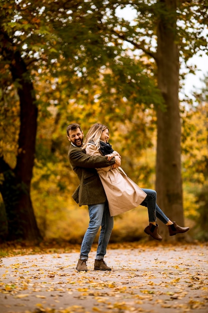 Pareja joven divirtiéndose en el parque de otoño