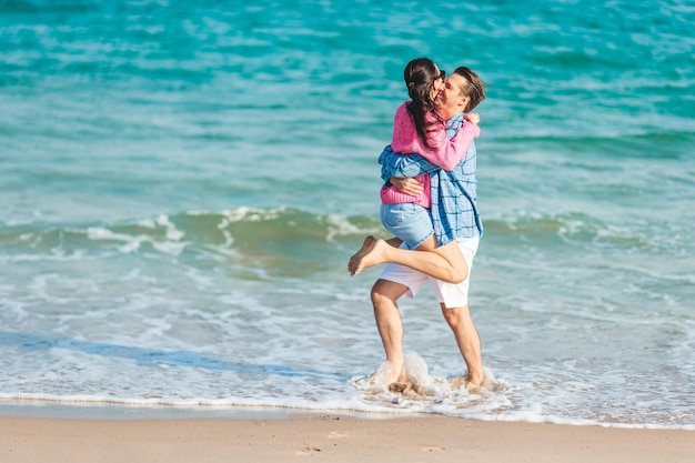 Pareja joven divirtiéndose en la playa chapoteando en aguas poco profundas