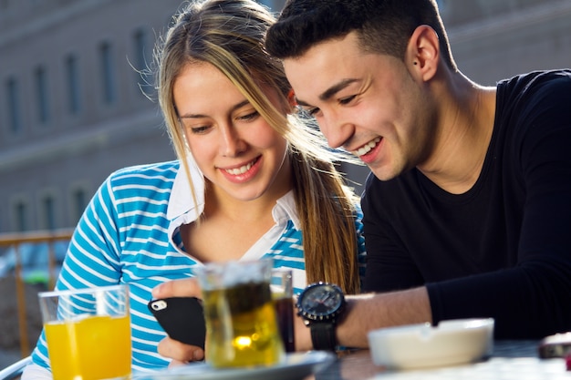 Pareja joven divirtiéndose con teléfonos inteligentes