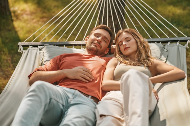 Pareja joven durmiendo en una hamaca en la naturaleza