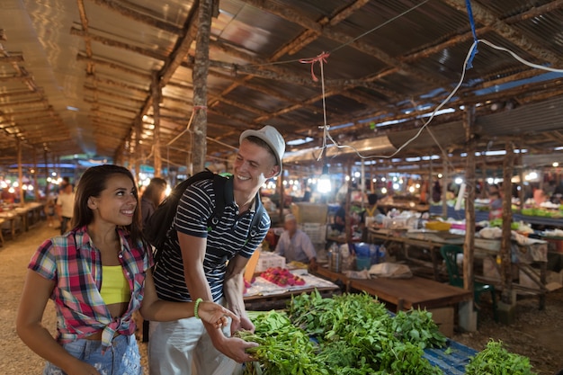 Foto pareja joven elegir hierbas en el mercado de verduras feliz sonriente hombre y mujer compras juntos en stre