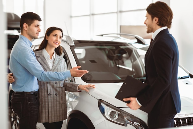 Una pareja joven elige un automóvil con un concesionario profesional