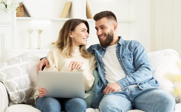 Pareja joven eligiendo una película en una laptop relajándose en casa