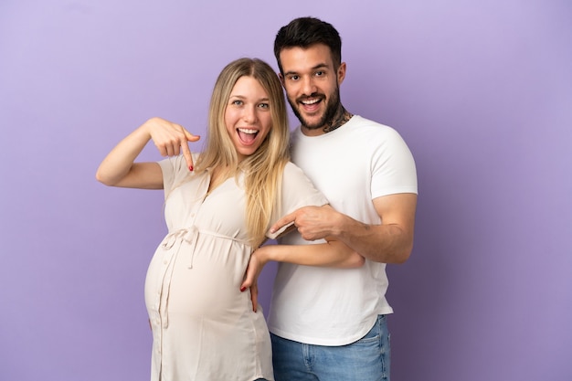 Foto pareja joven embarazada y apuntando al vientre