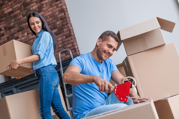 Pareja joven empacando una caja de cartón para mudarse a un nuevo apartamento