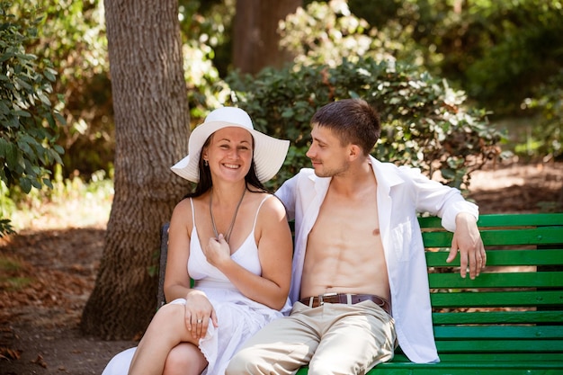 Una pareja joven enamorada en un banco del parque con ropa ligera en un día de verano