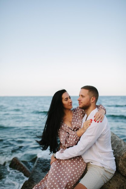 Pareja joven enamorada Hombre y mujer atractivos disfrutando de una velada romántica en la playa viendo la puesta de sol