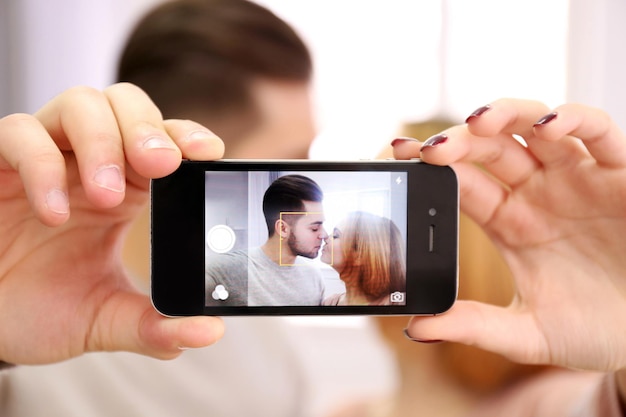 Una pareja joven enamorada tomándose una foto con un teléfono móvil de cerca