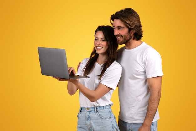 Foto una pareja joven y entusiasta colaborando usando una computadora portátil que muestra el trabajo en equipo