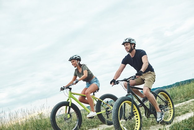 Pareja joven está en bicicleta en fatbikes y con cascos foto recortada