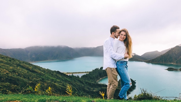 Una pareja joven está caminando en las Azores un hombre abraza a una mujer por detrás por la cintura