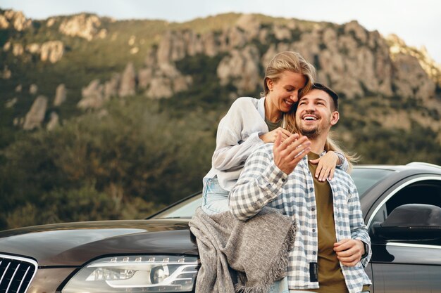 Pareja joven está en viaje romántico a las montañas en coche