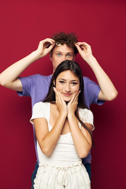 Una pareja joven estilo verano posando emociones de moda fondo rojo.