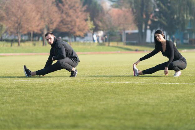 Pareja joven estirando antes de correr en el área del parque de la ciudad entrenando y haciendo ejercicio para Trail Run Marathon Endurance Fitness Concepto de estilo de vida saludable al aire libre