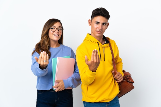 Pareja joven estudiante en blanco invitando a venir con la mano. Feliz de que hayas venido