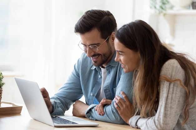 Una pareja joven y feliz de raza mixta viendo videos divertidos en la computadora.