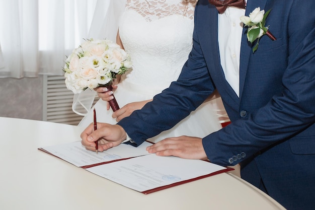 Pareja joven firmando documentos de boda Centrarse en la mano