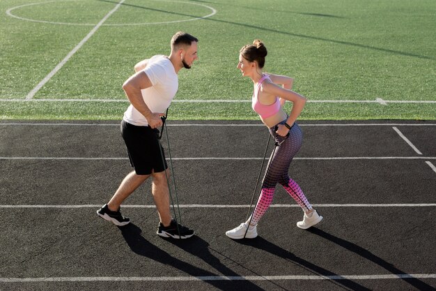 Pareja joven fitness entrena en el estadio en verano con un expansor elástico